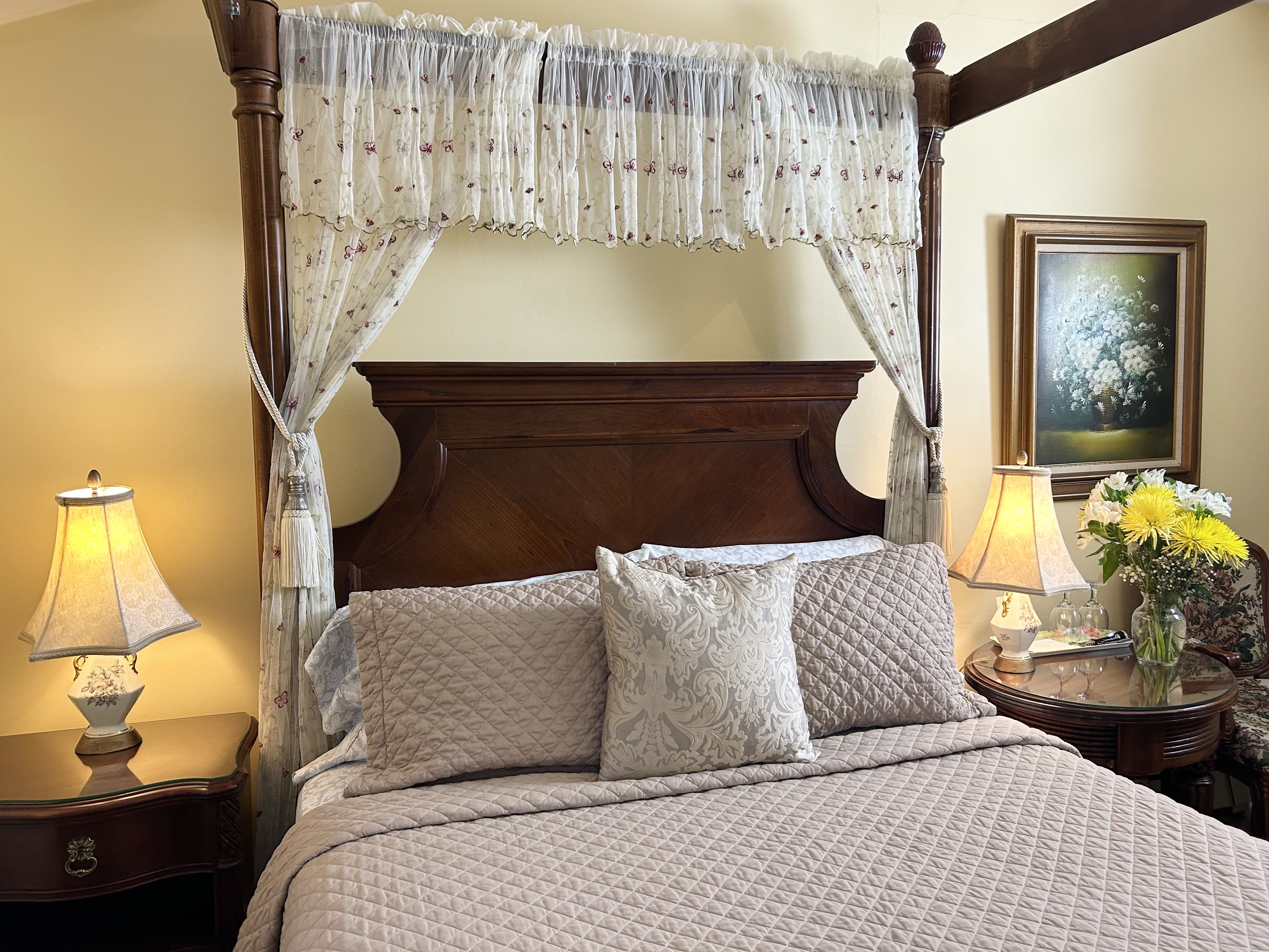 "Front view of four poster walnut queen size bed with two side tables and two lamps"