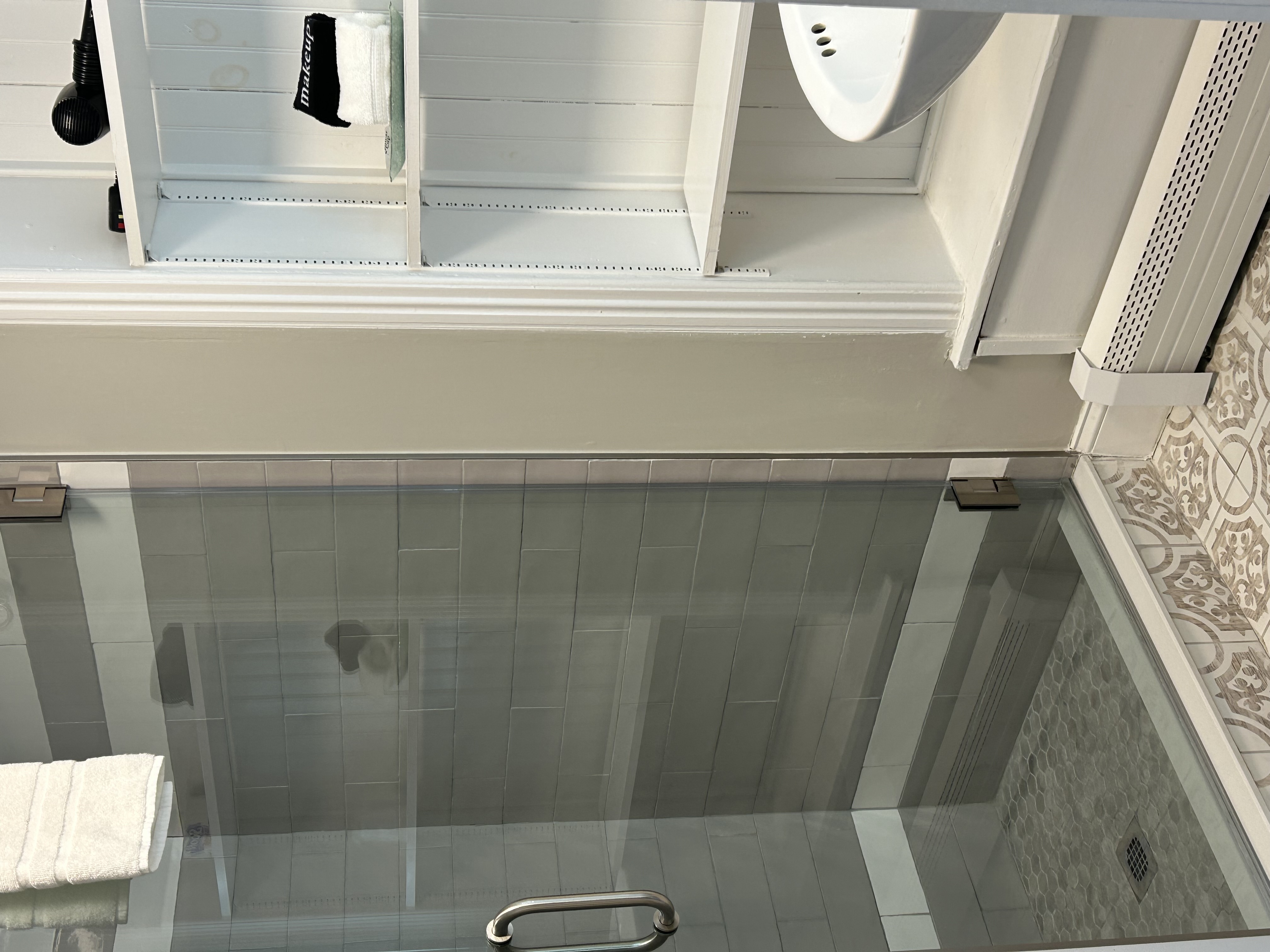 Looking into the bathroom with a glass door tile shower and wood shelves