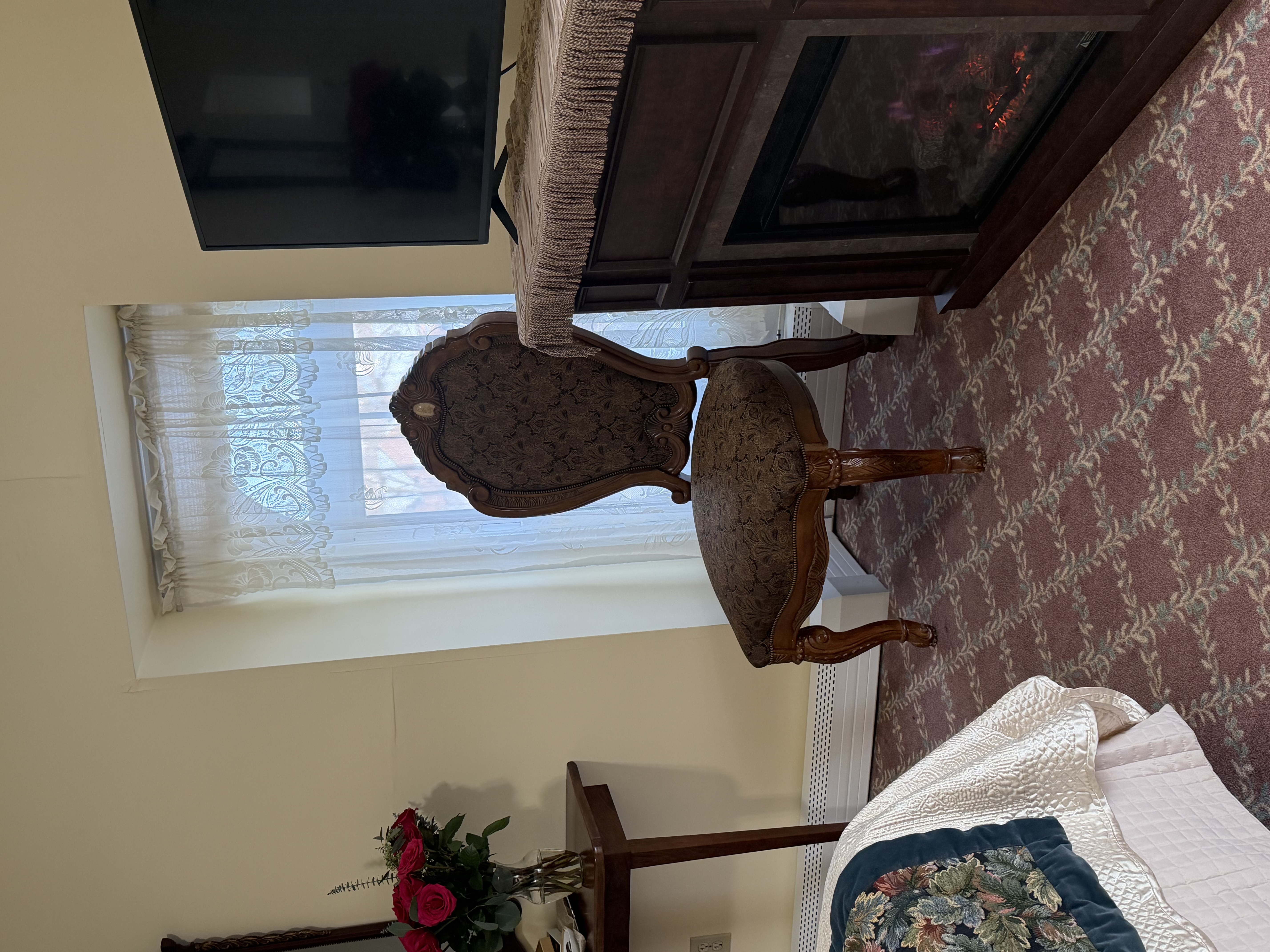 View of electric fireplace, TV, window with chair