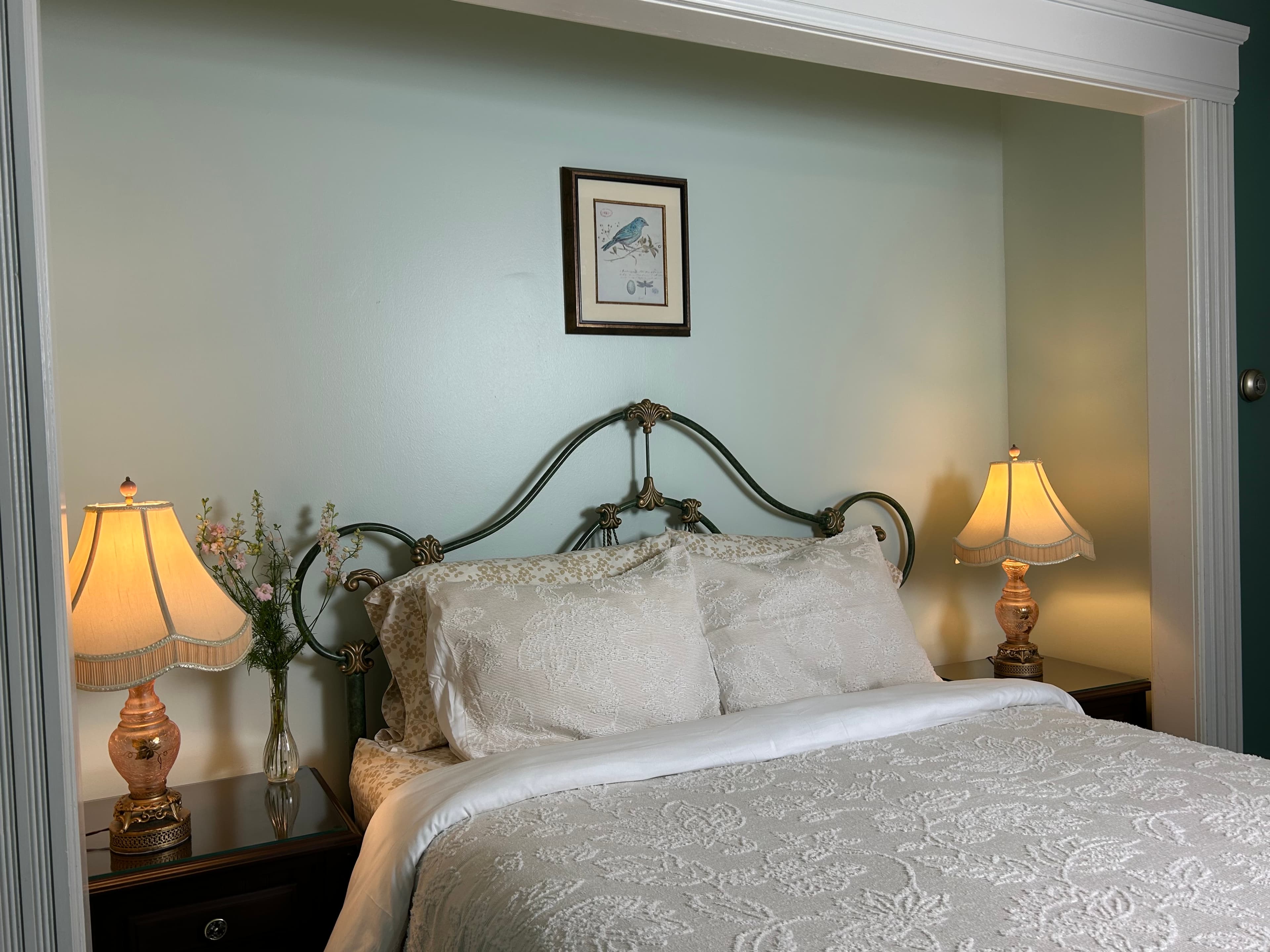 View of queen size bed with 2 side tables and 2 lamps