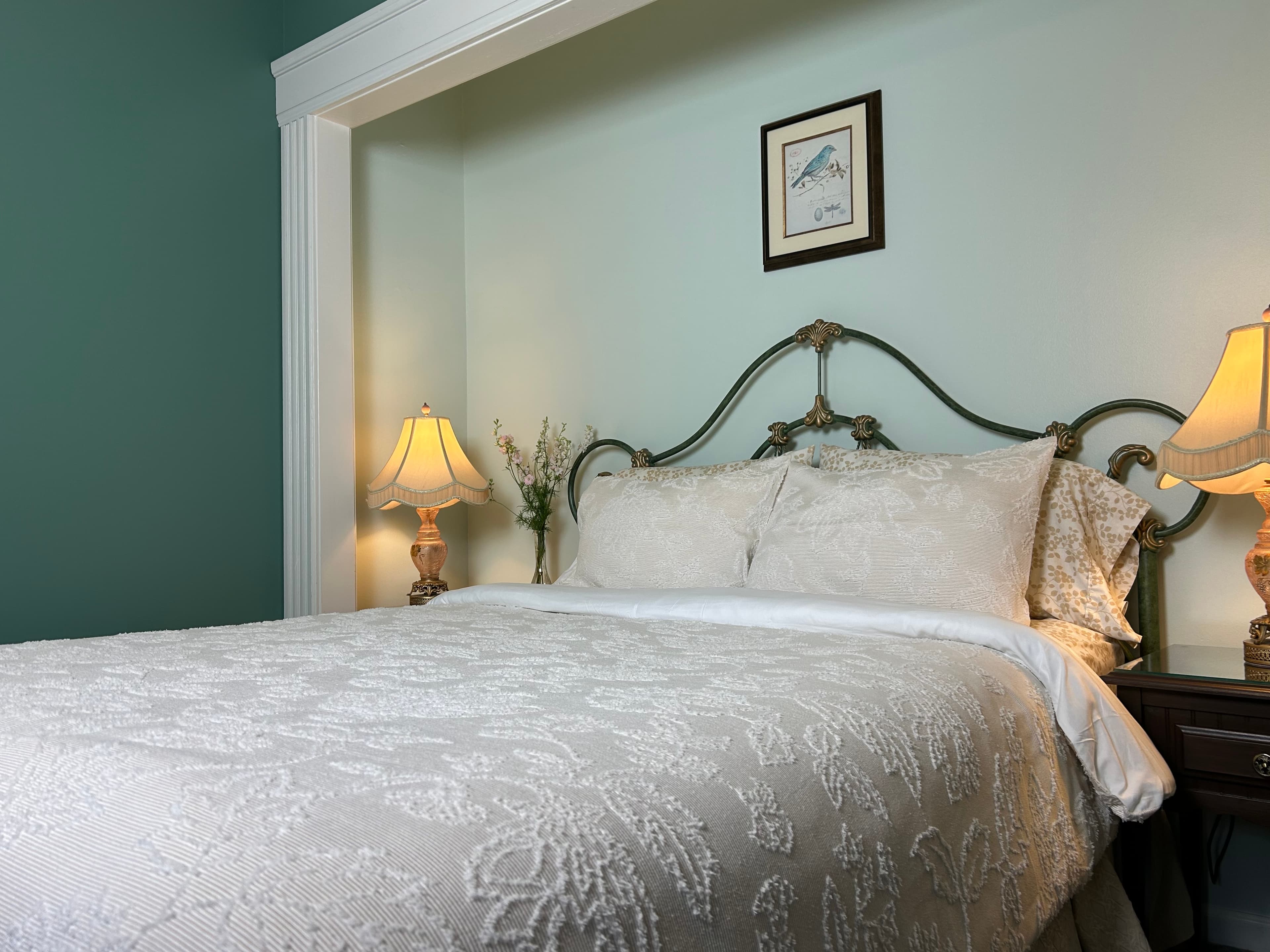 View of queen bed, 2 side tables with lamps and flowers