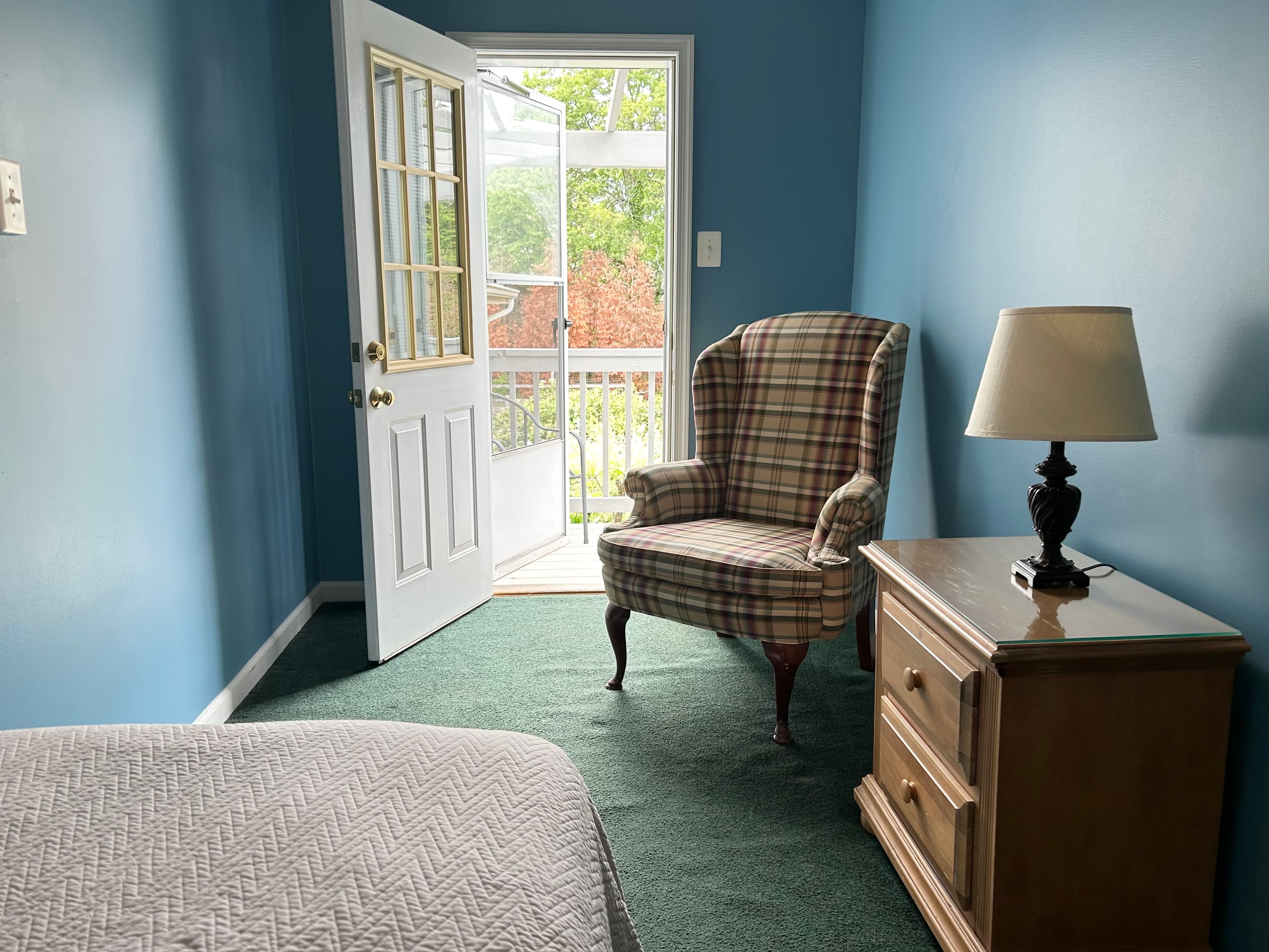 View of door to balcony with chair, night table and lamp