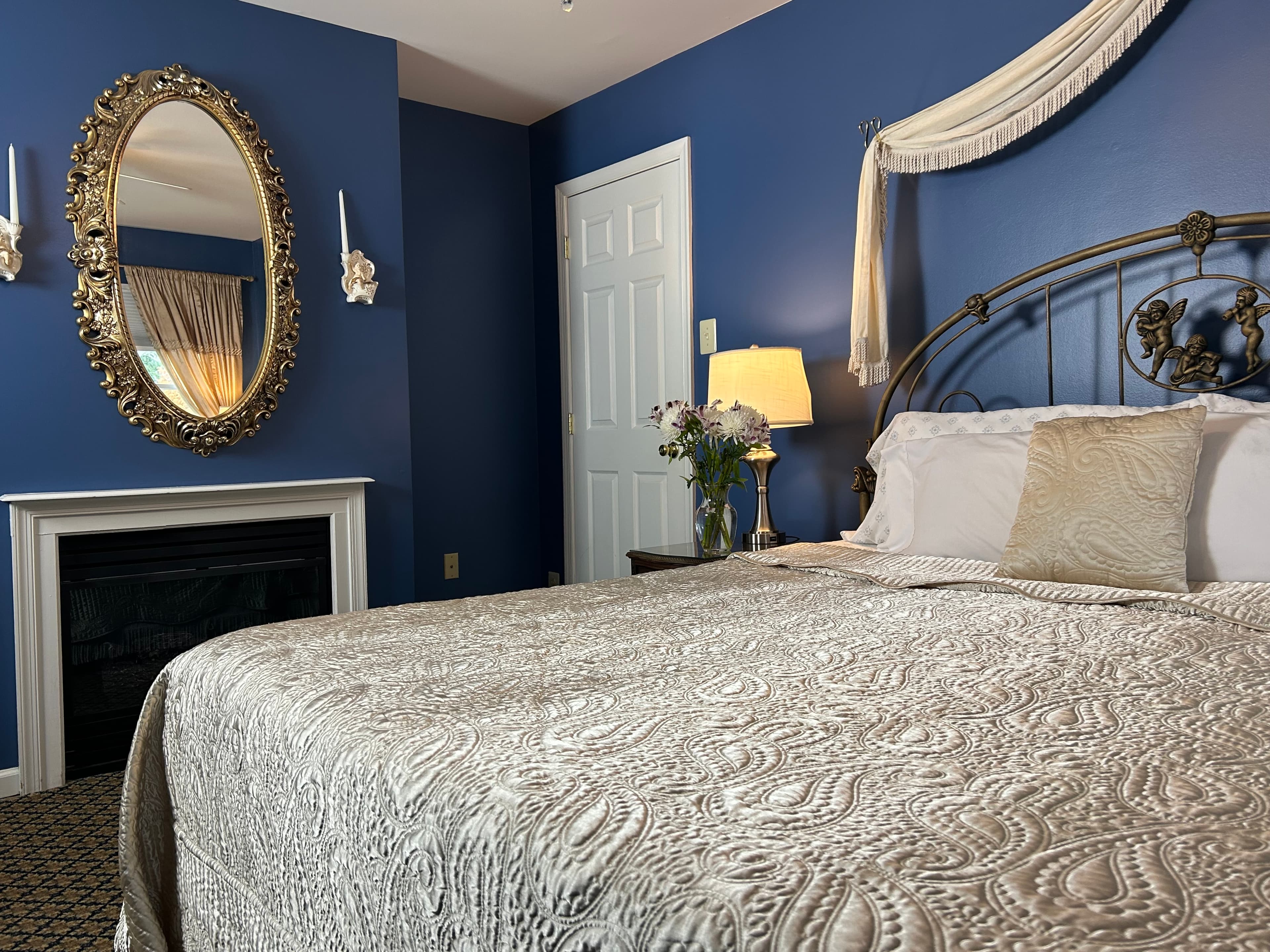 View of king size bed with side tables, lamps and gas fireplace
