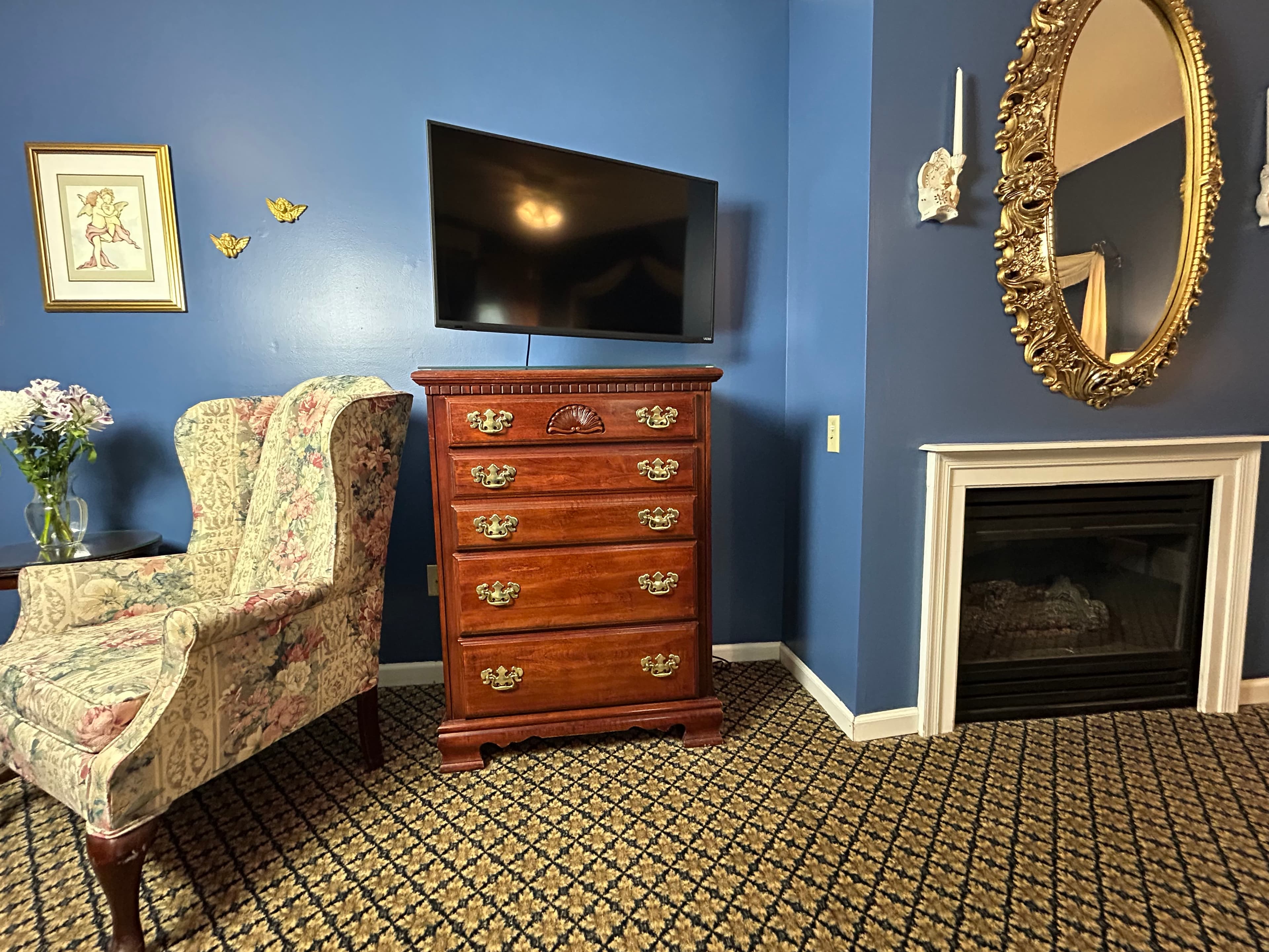 View of gas fireplace, dresser. TV and high back chair