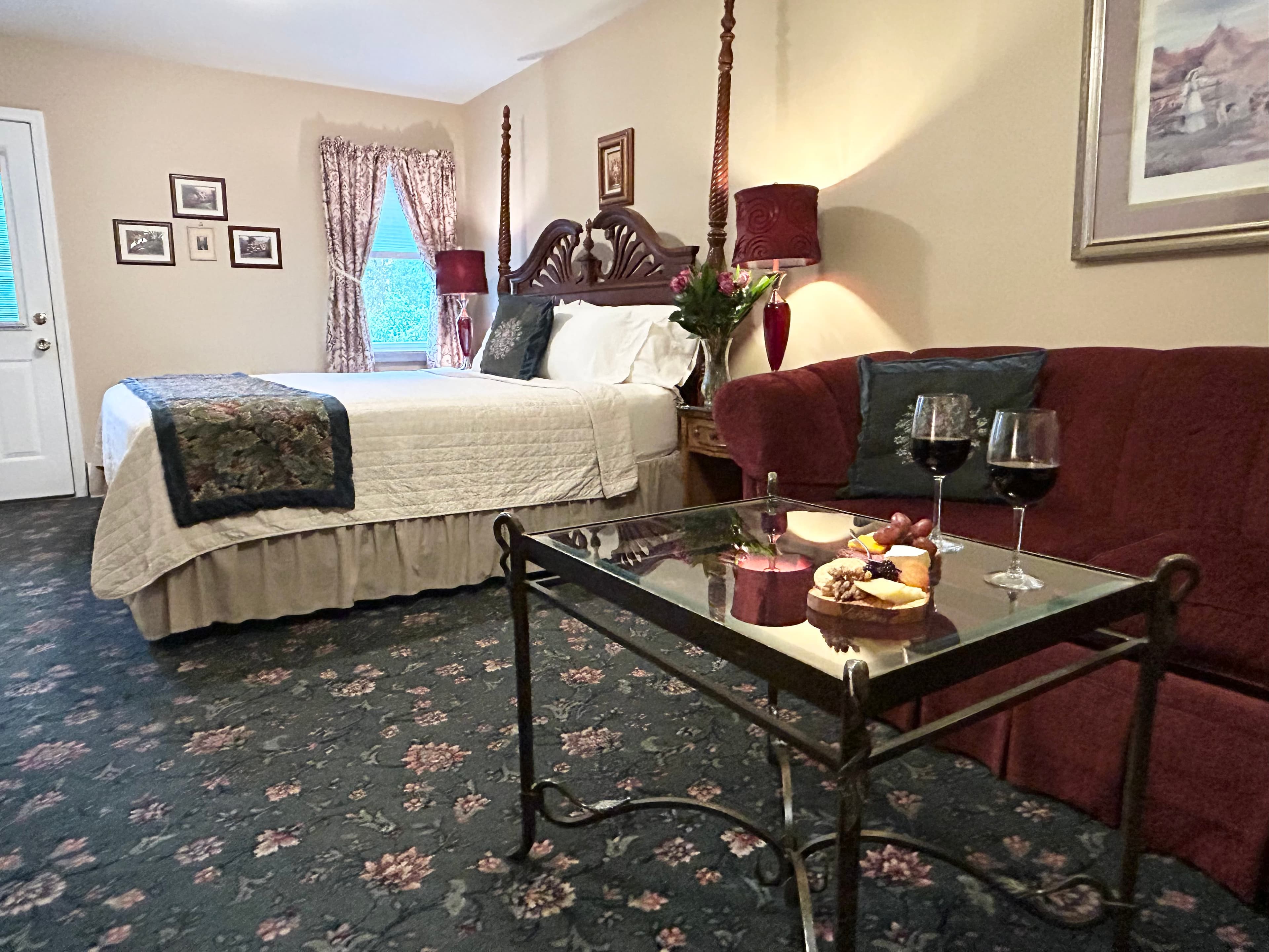 Room view from gas fireplace with king bed, couch, table, nightstand and flowers