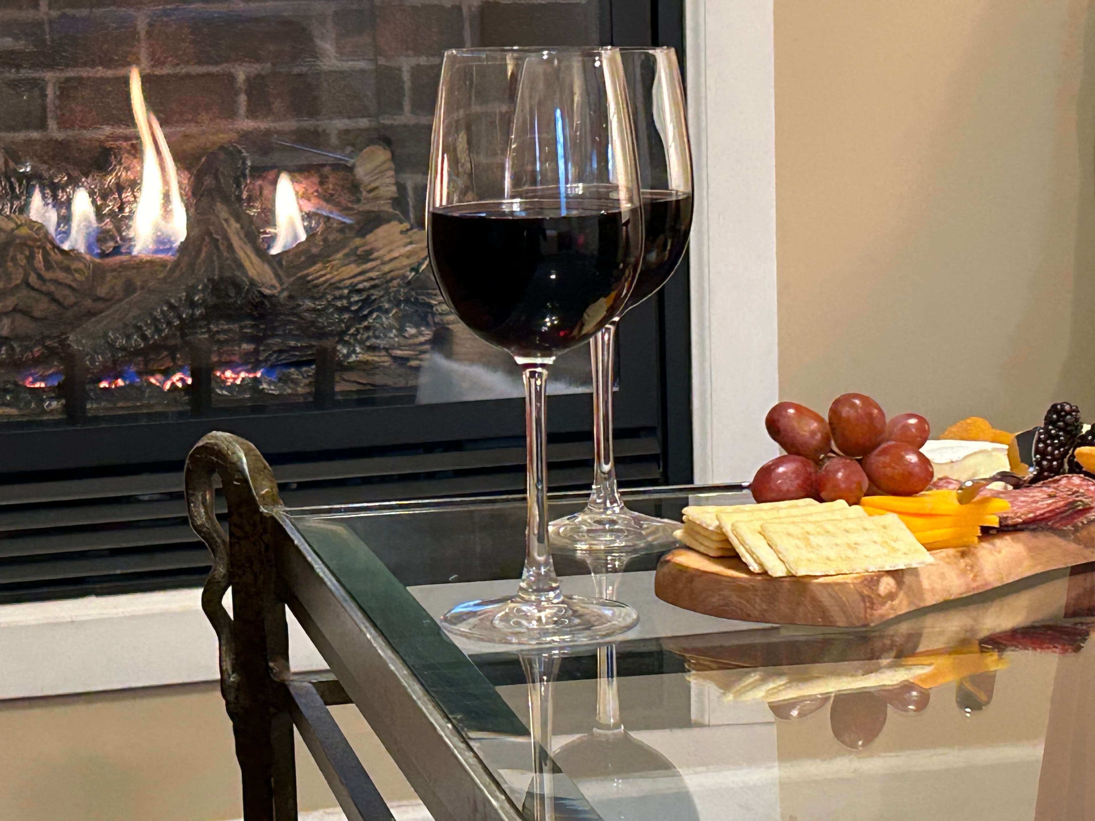 Close up of wine and charcuterie board with gas fireplace in background