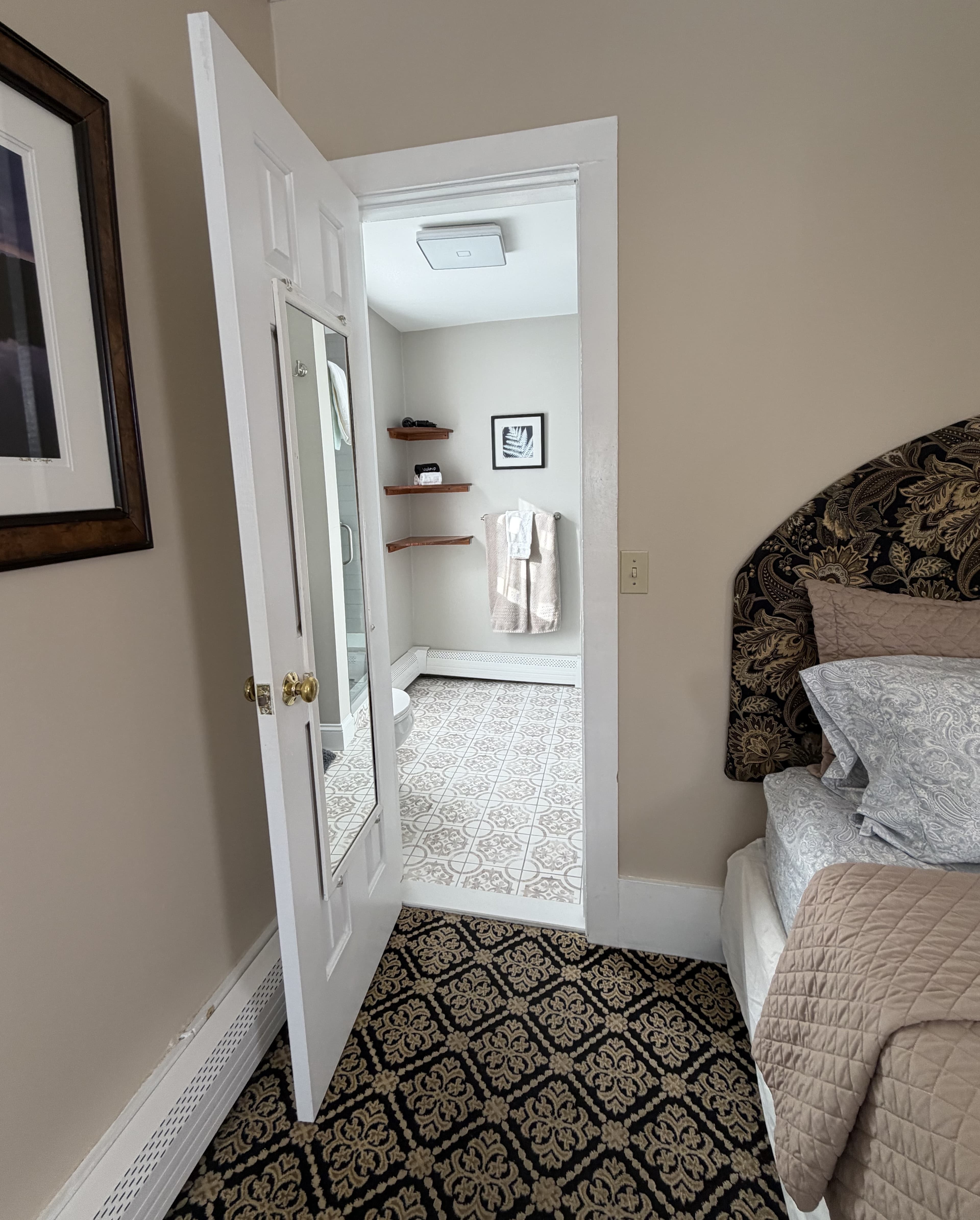 View of door to the bathroom next to the bed
