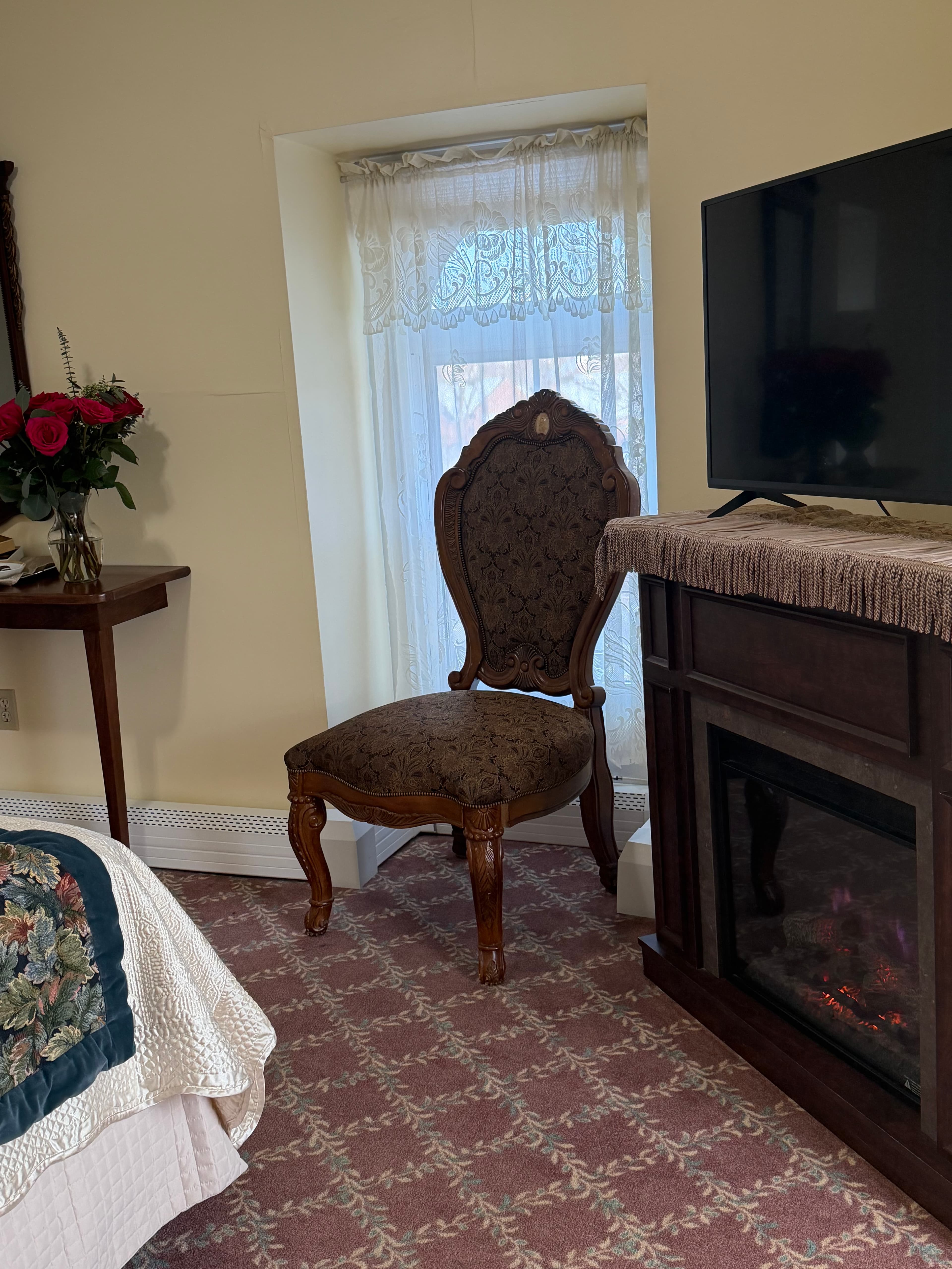 View of electric fireplace, TV, window with chair