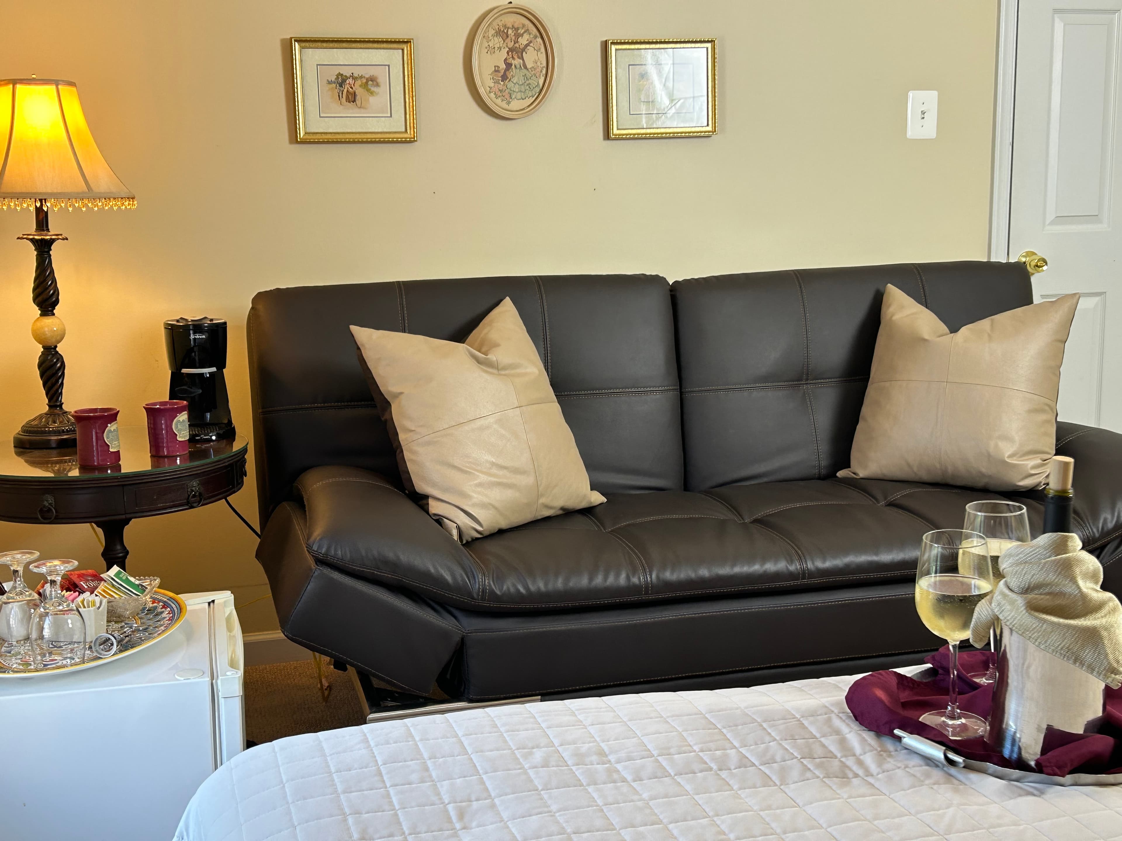 View of couch with table, lamp, mini fridge & coffee/ tea amenities
