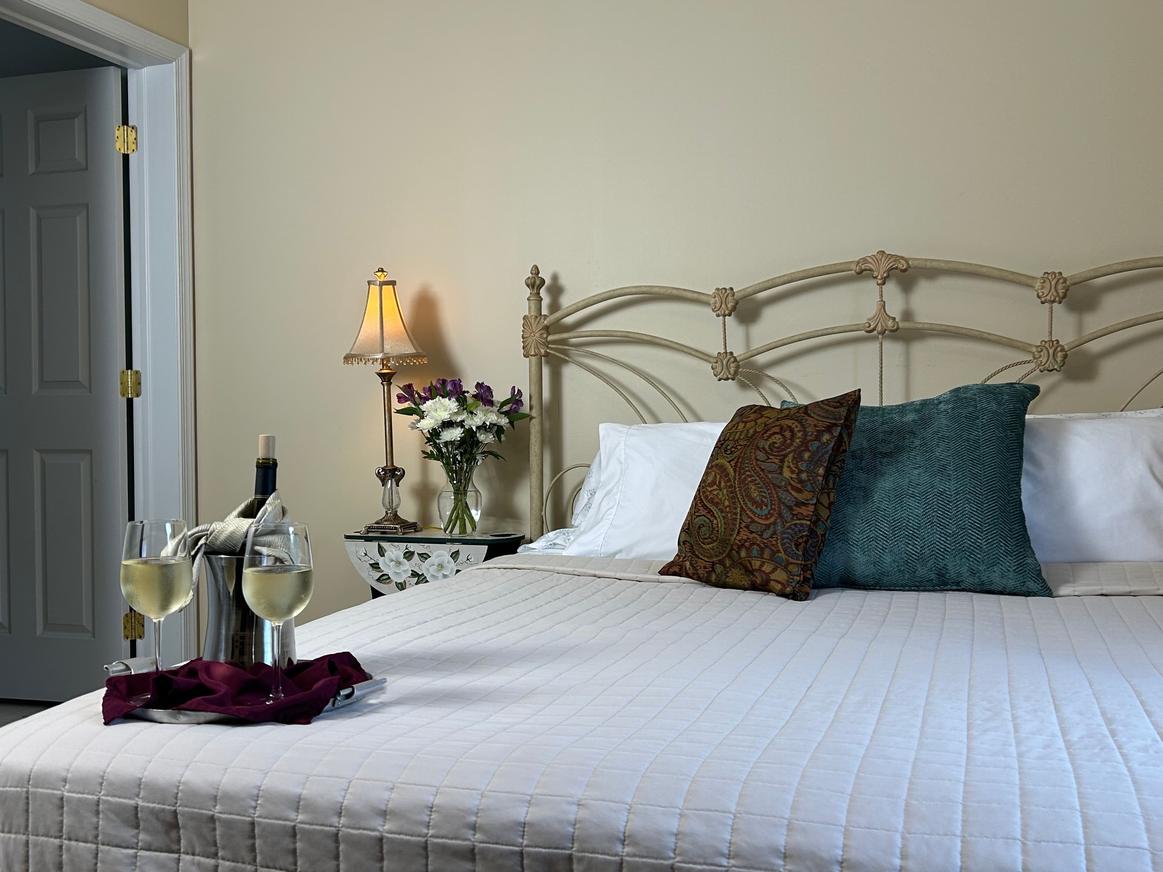 View of king bed, side table & lamp with bathroom door