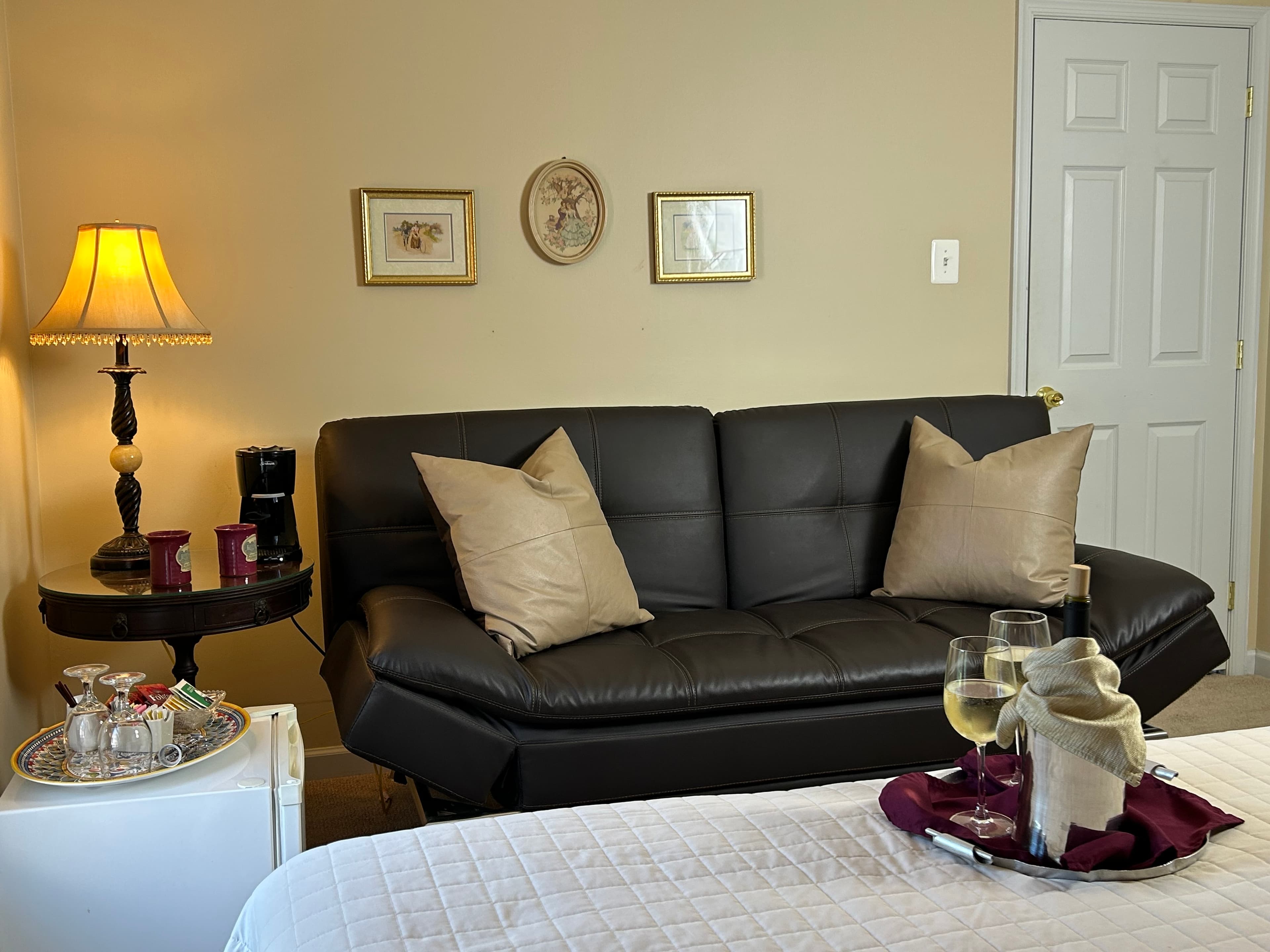 View of sitting area with couch, side table,lamp & mini fridge with amenities