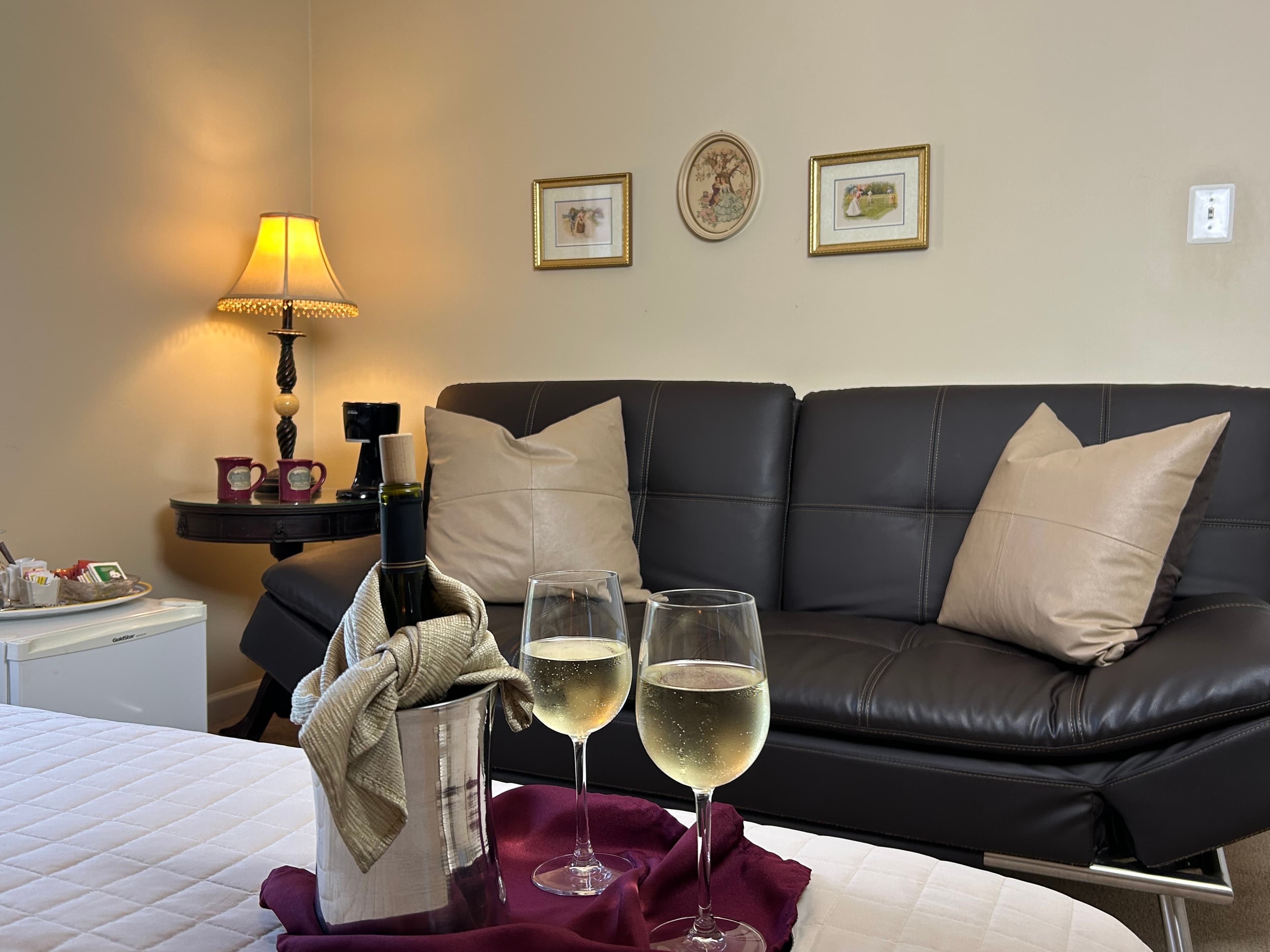 View of sitting area with wine & wine glasses on the bed