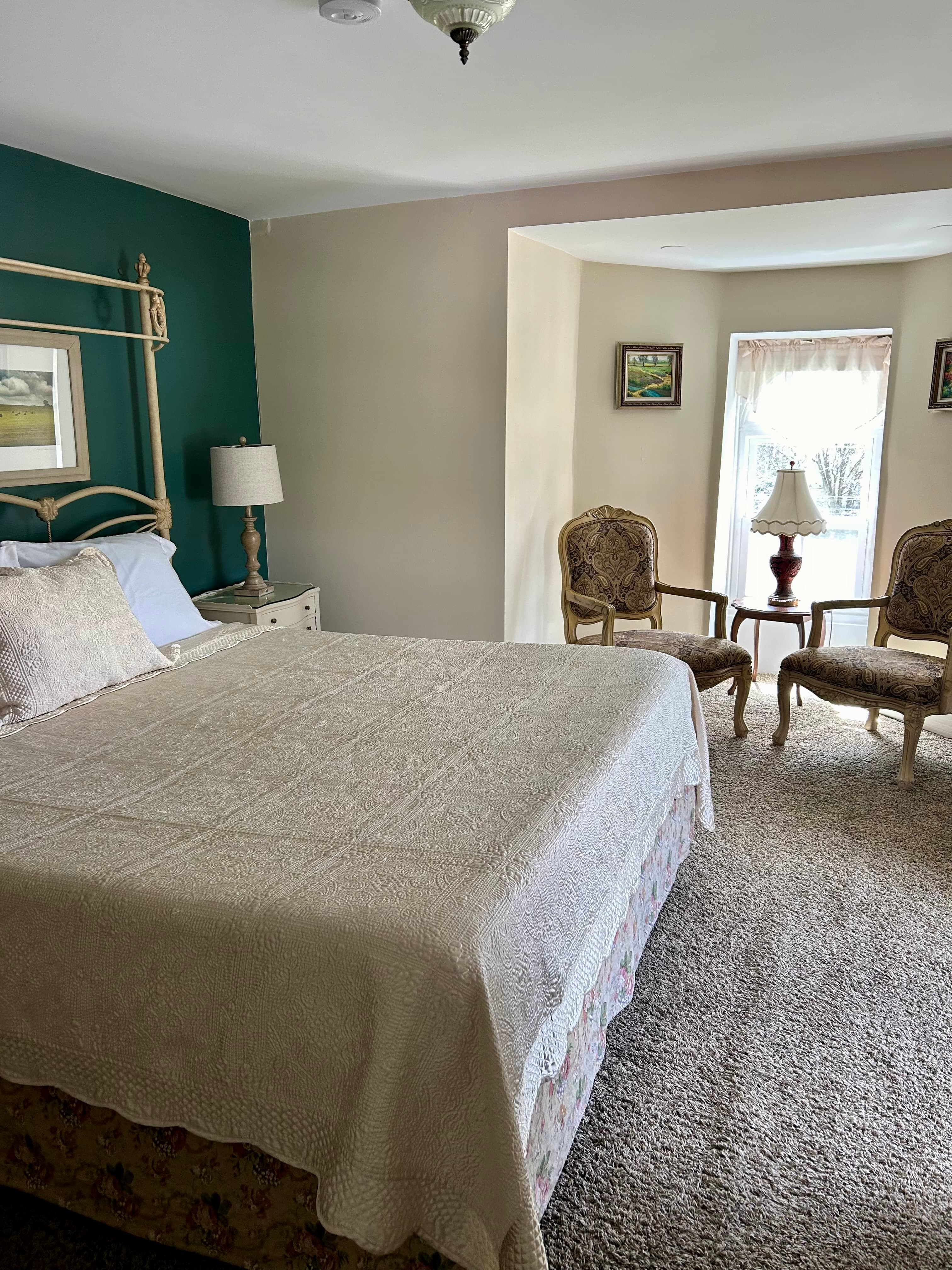 sitting area with 2 chairs, 2 autumn paintings and a lamp in the center