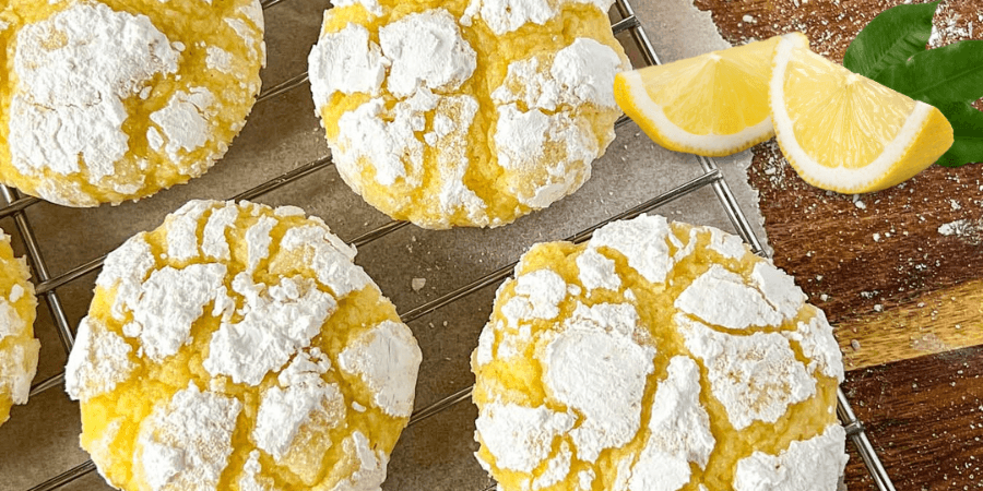 Pineapple lemon crinkle cookies dusted with powdered sugar on a cooling rack.