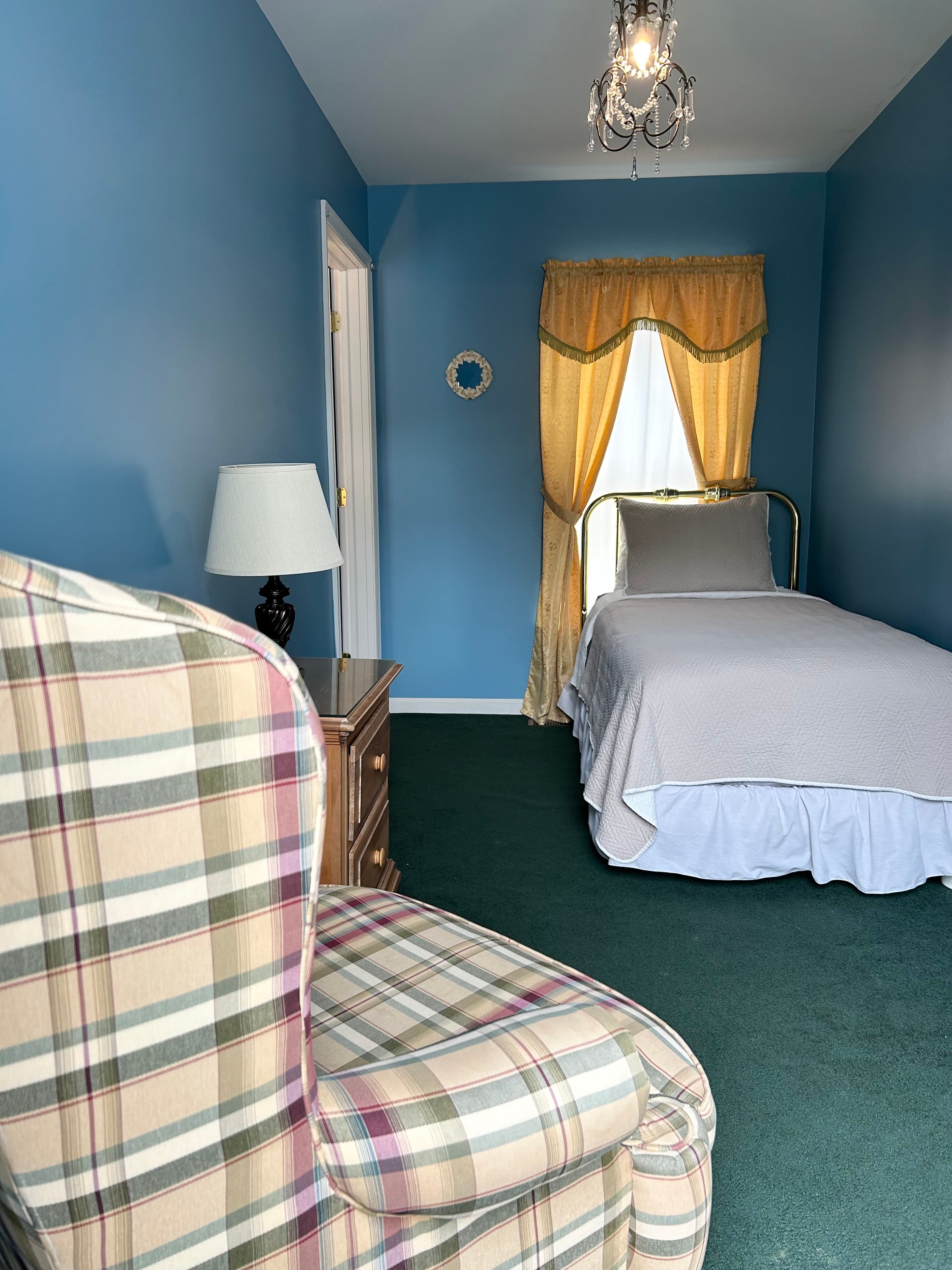 View of twin bed from balcony, side table with lamp and chair