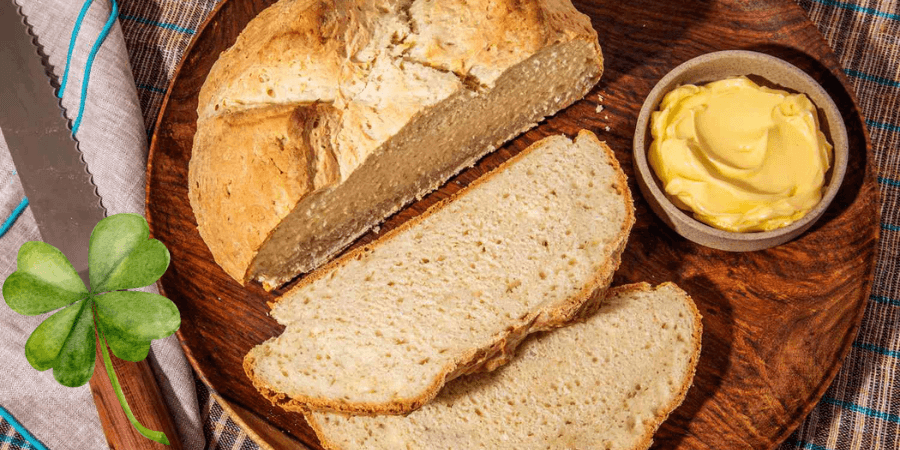 Sliced Irish soda bread on a wooden board with a small bowl of butter.