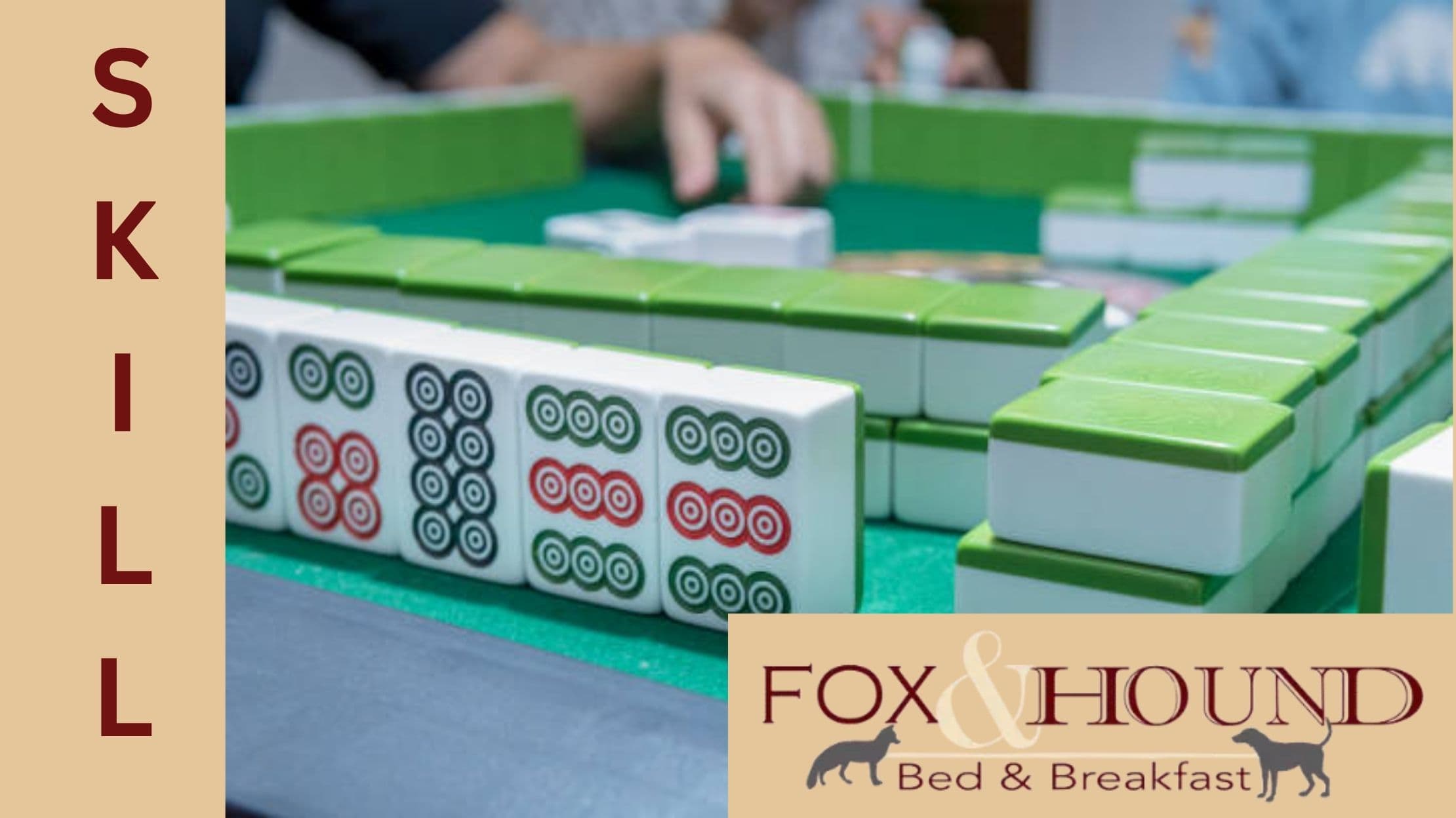 A close-up of mahjong tiles on a table with hands preparing to play, alongside a logo for Fox & Hound Bed & Breakfast.