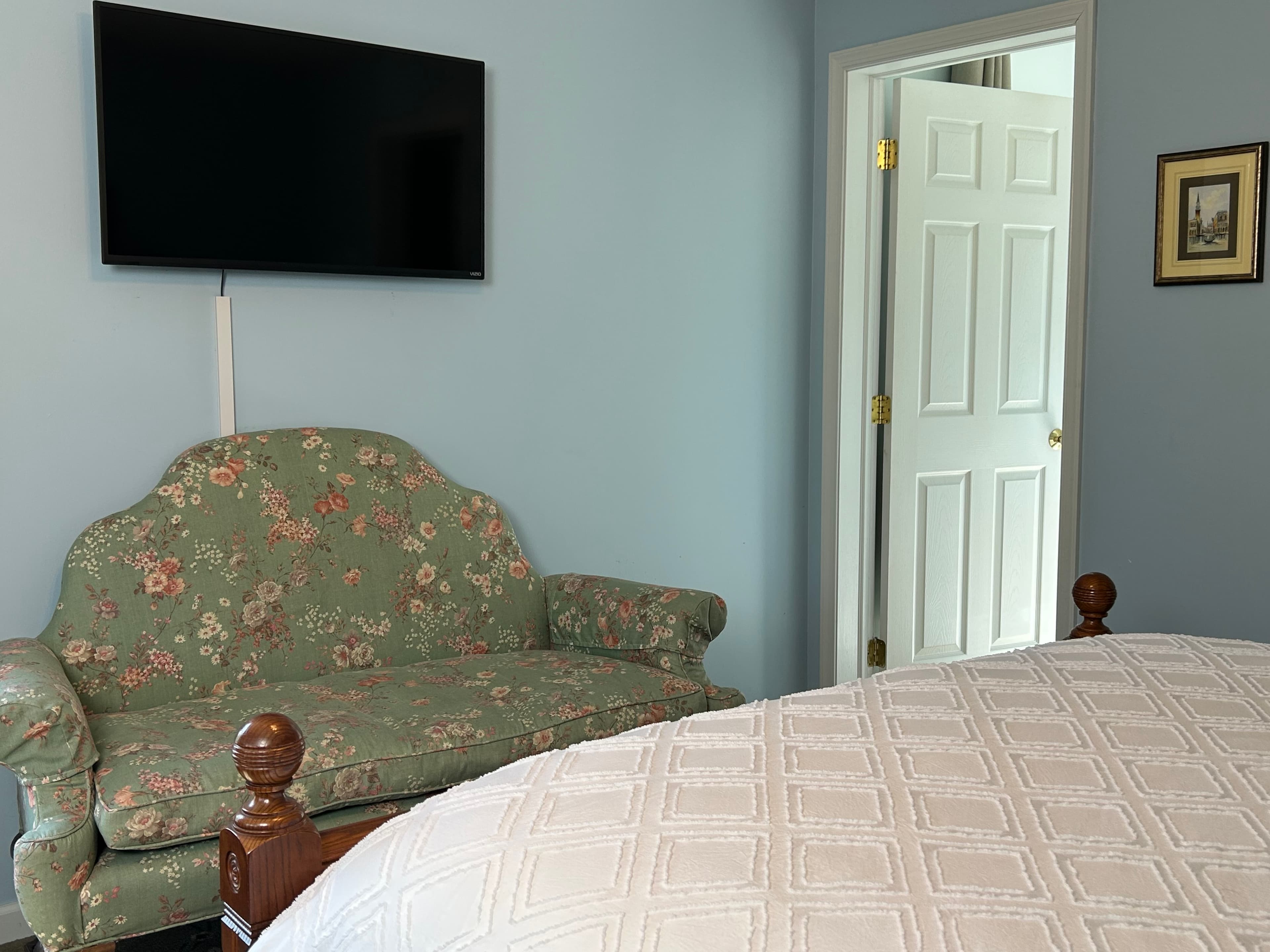 View of sitting area with couch, TV and door to bathroom
