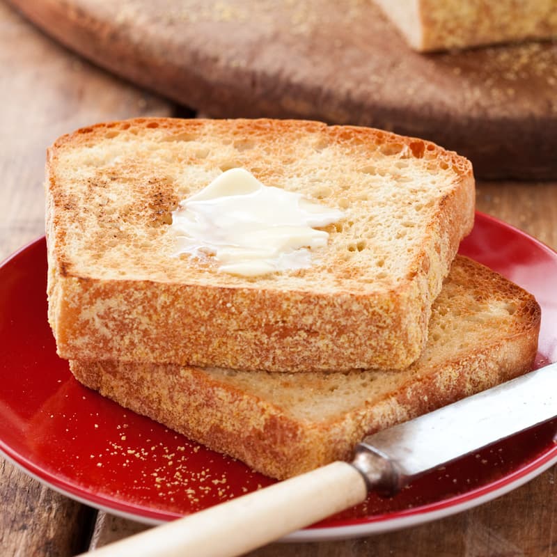 Two slices of toasted bread with a pat of butter on a red plate.