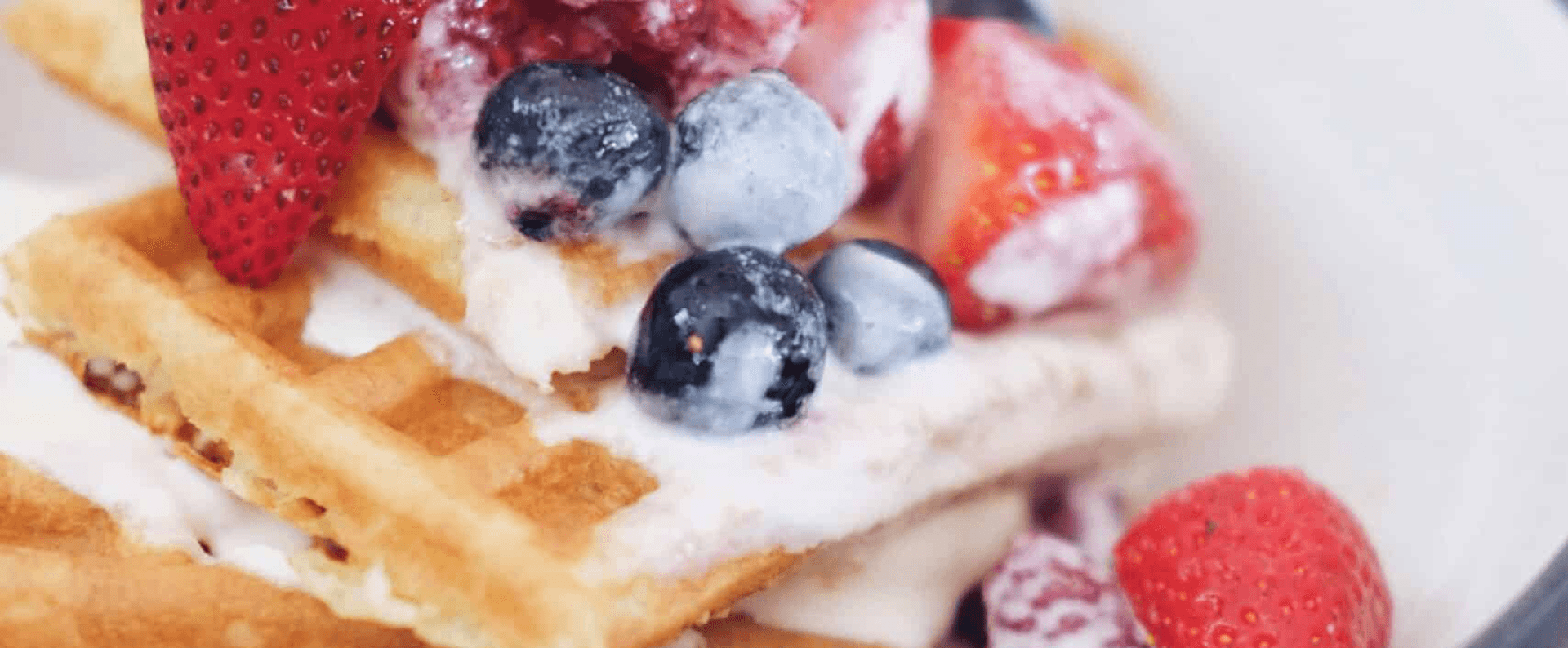 Close-up of waffles topped with strawberries, blueberries, and cream.