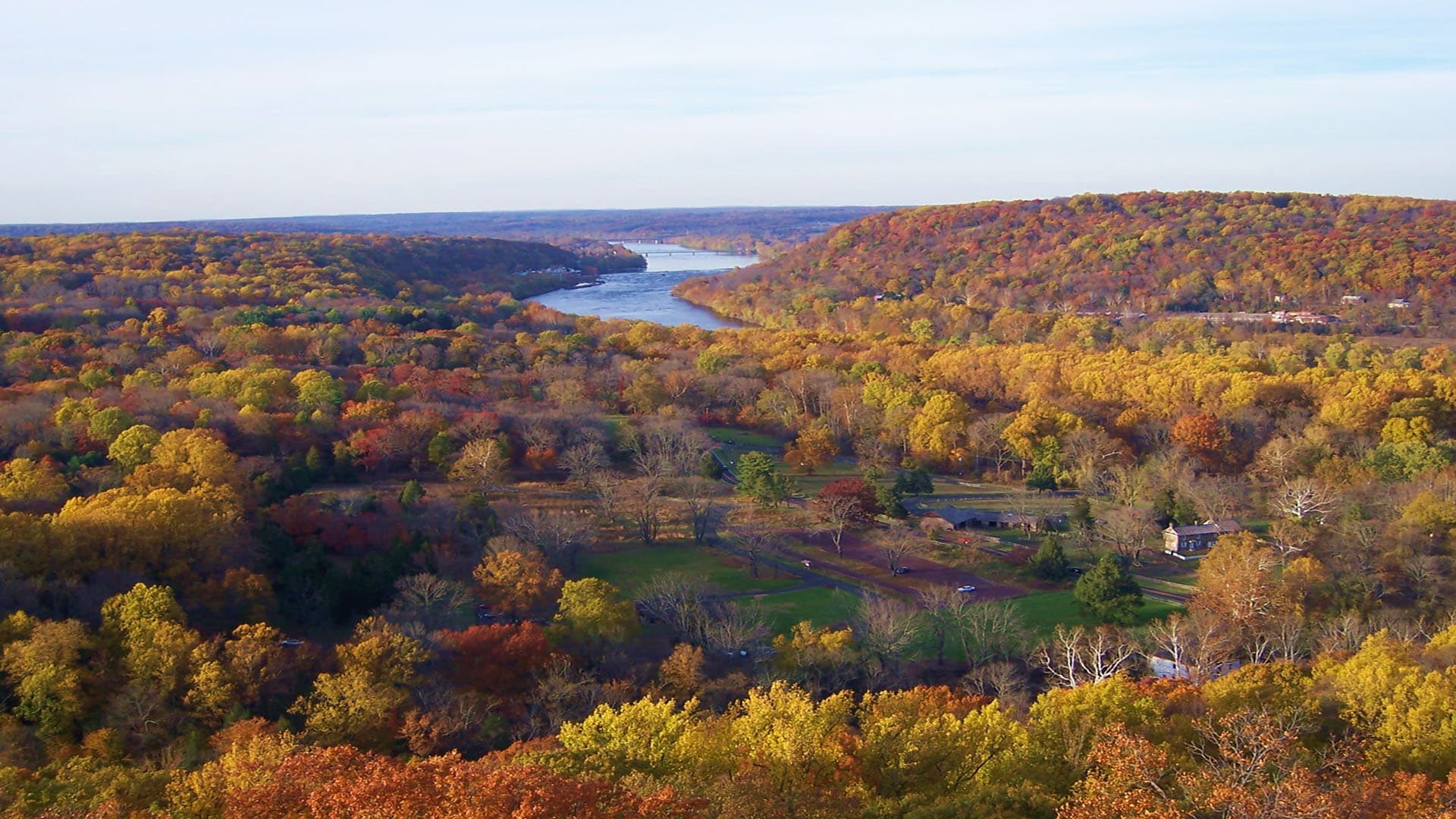 A panoramic view of a river winding through colorful autumn foliage.