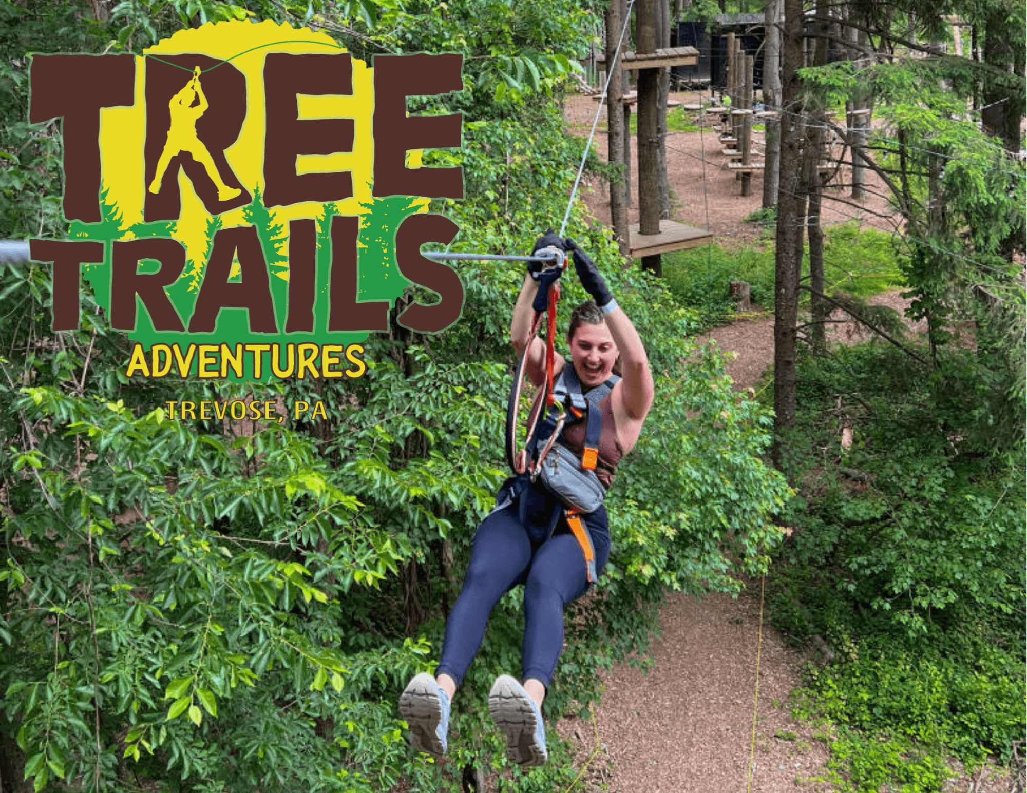 A person zip-lining through a lush green forest at Tree Trails Adventures in Trevose, PA.