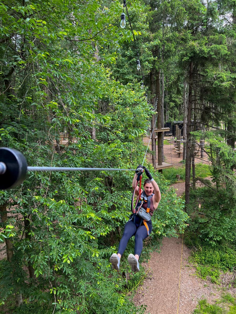 A person zip-lining through a forested area.