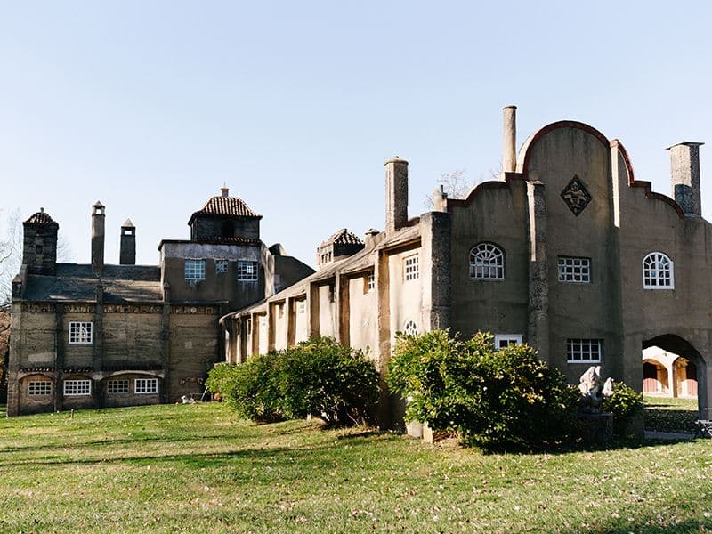 An architectural structure with unique design features surrounded by grass and shrubs.