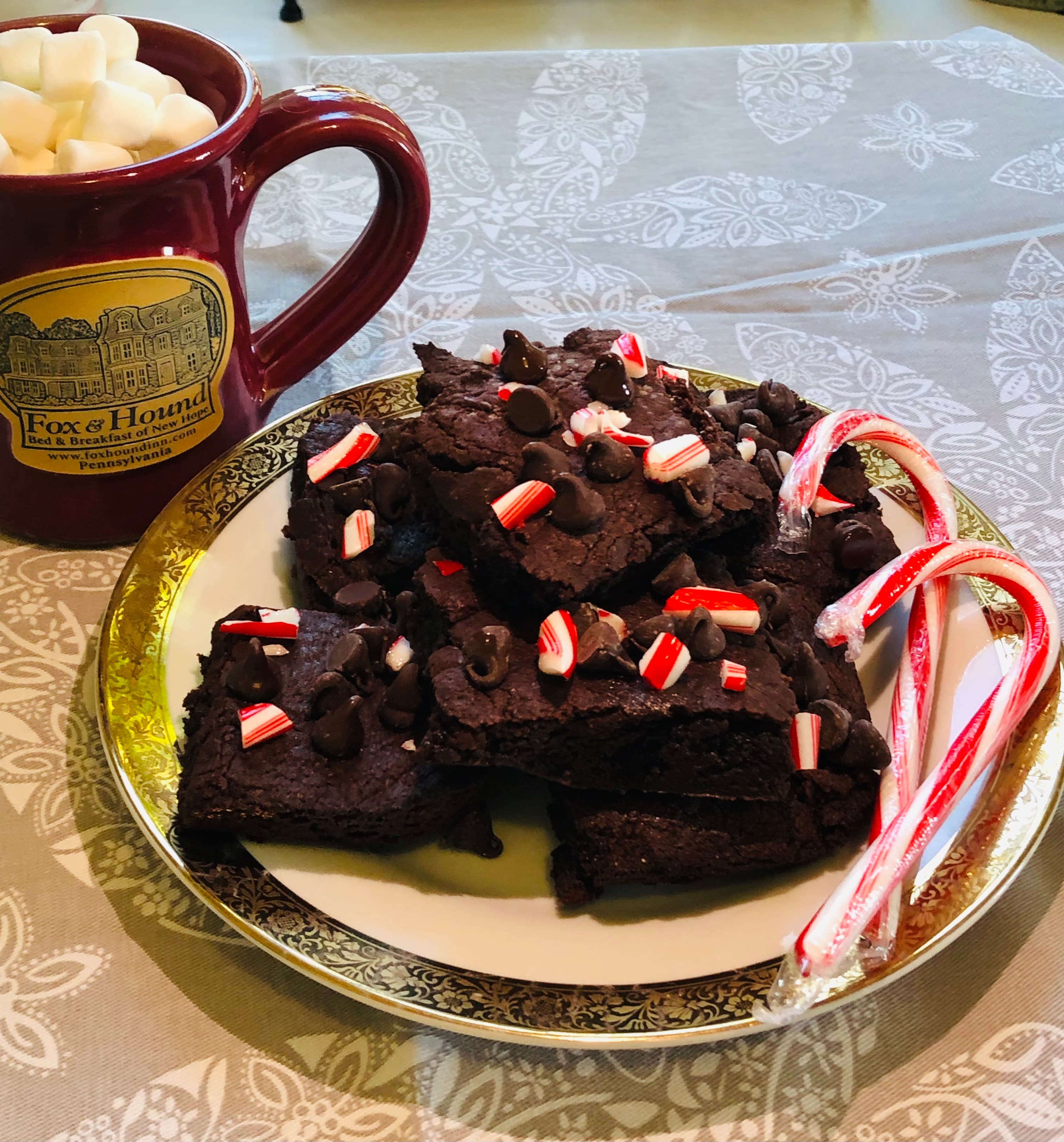 Plate of homemade dark chocolate peppermint brownies with a steaming cup of hot cocoa